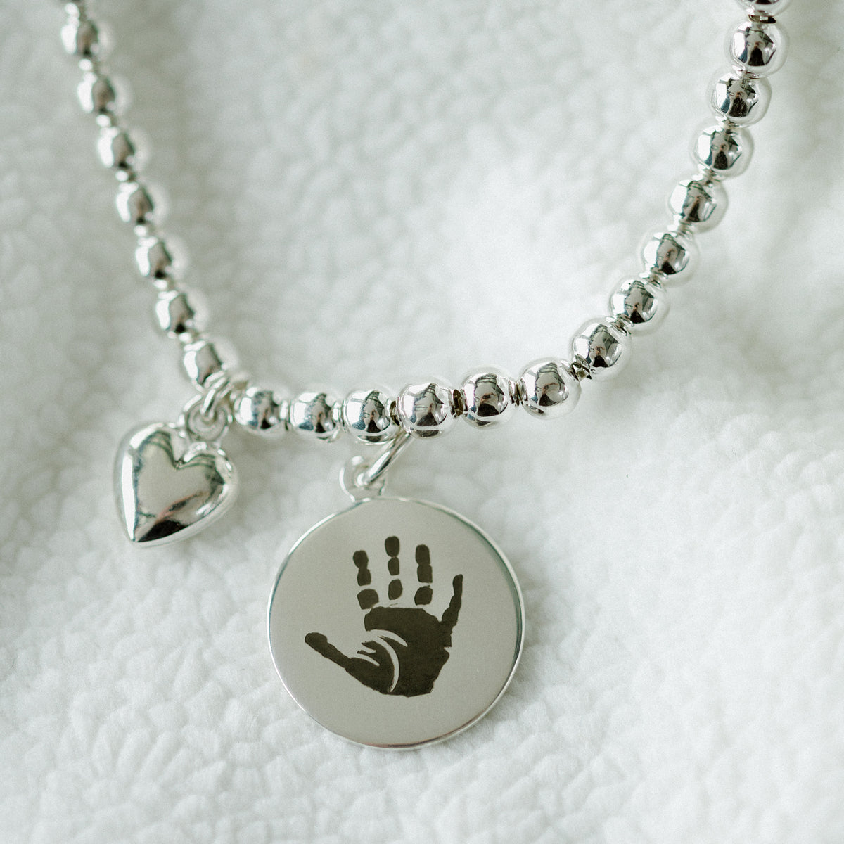 Silver hand and footprint pendant on a slider bracelet